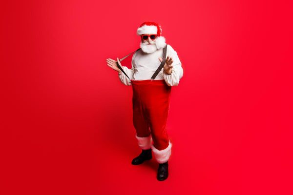 Full length body size of cheerful positive optimistic glad Santa pulling pants suspenders ready to feast festive party congrats congratulations best wishes sale discount isolated over red background
