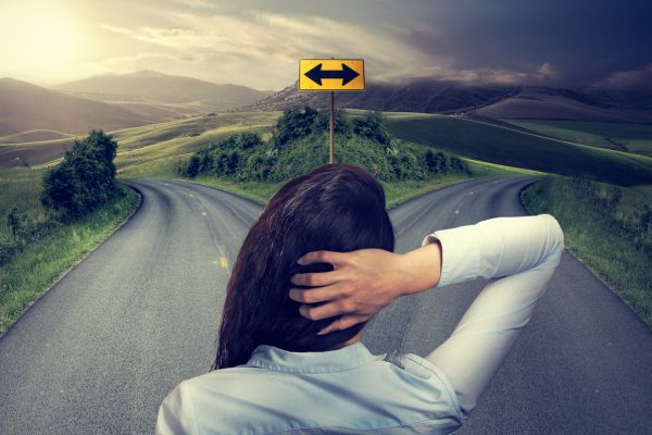 business woman in front of two roads thinking deciding