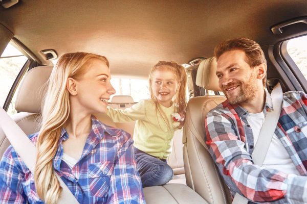 To travel is to live. Smiling family sitting in the car and driving. Family road trip