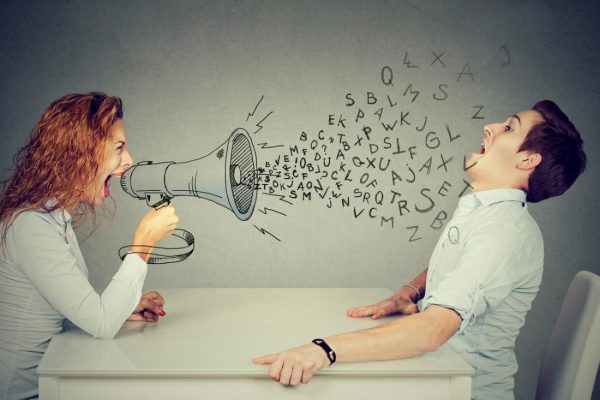 angry young woman with megaphone shouting at stressed scared man blown away by wave of alphabet letters