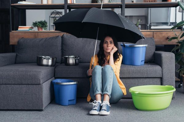 Pensive brunette woman sitting on floor with umbrella