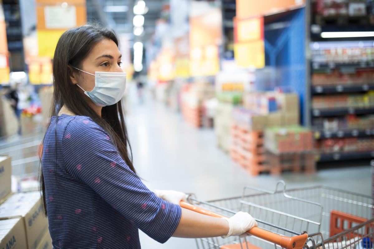 Woman with face mask, shopping for groceries in a supermarket during