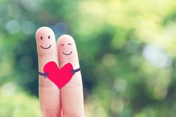 Happy loving fingers holding red heart
