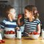 Happy children girl and boy brother and sister eating strawberries with milk