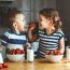 Happy children girl and boy brother and sister eating strawberries with milk